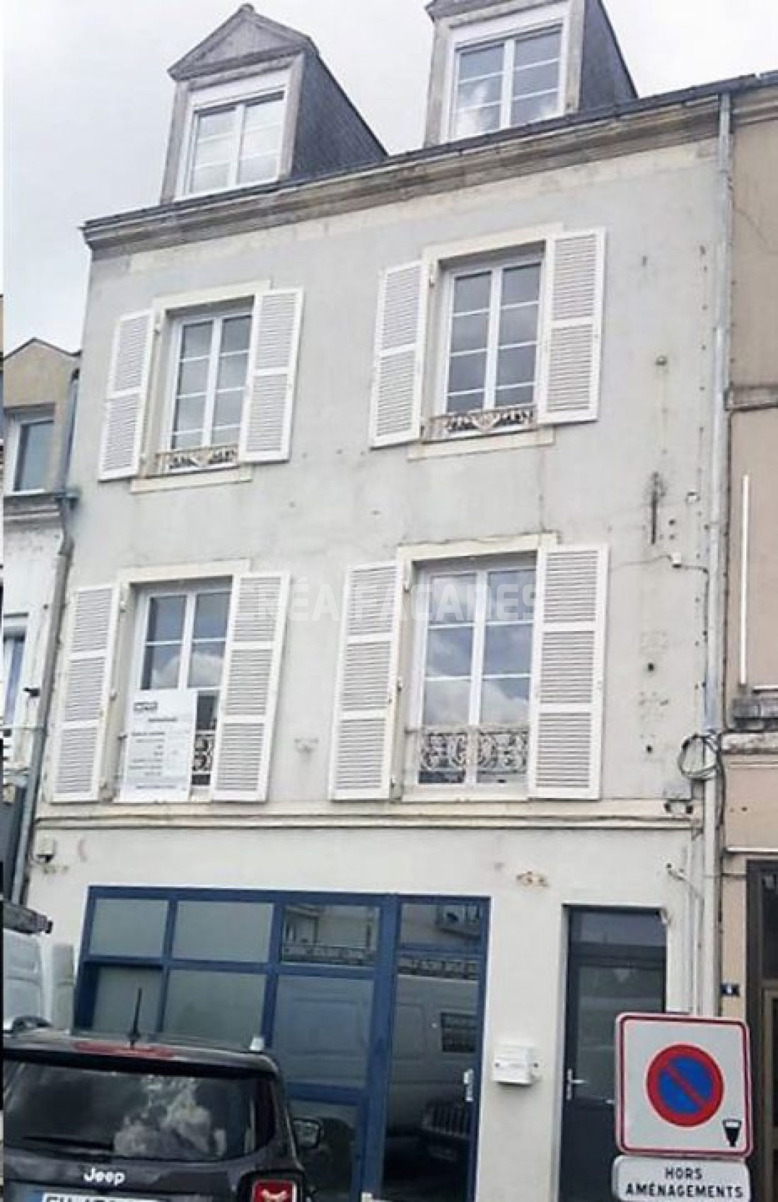 Façade d'immeuble avec volets, Créa'Façades affichée sur la fenêtre.